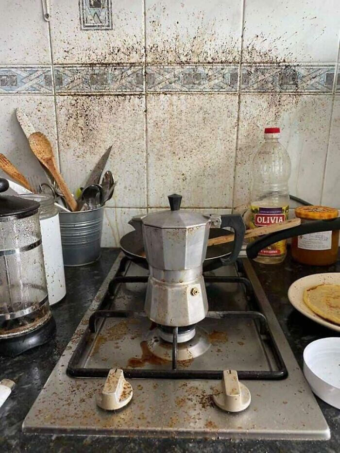 A very messy kitchen with a stovetop and backsplash covered in splattered food, a true kitchen fail.