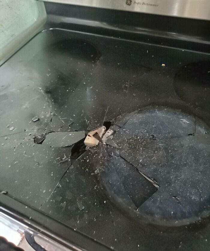 A broken glass stovetop with a metal object in the middle, showing a major kitchen fail.