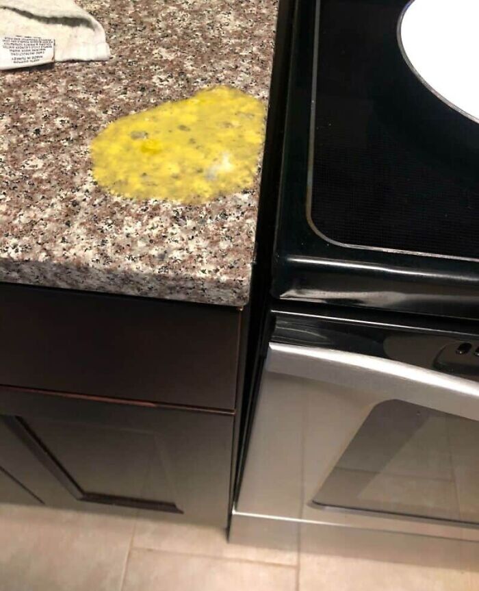 Scrambled eggs spilled on a kitchen counter next to a stove, an example of unfortunate kitchen fails.