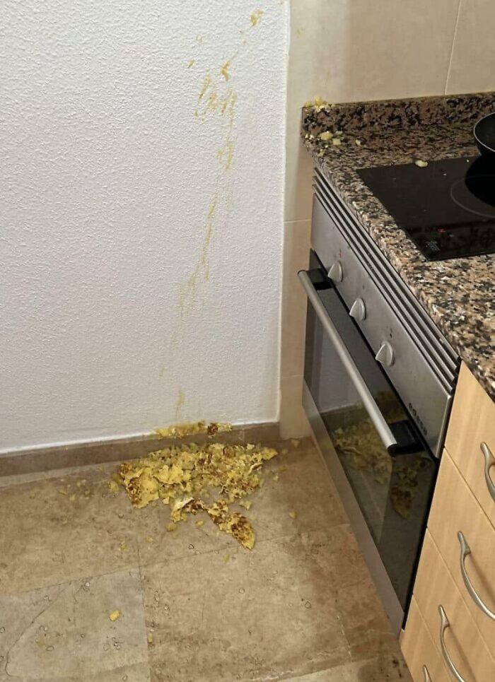 Scrambled eggs splattered across a kitchen floor and wall, an unfortunate kitchen fail mess.
