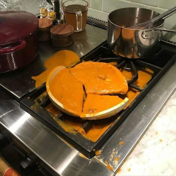 A vibrant orange sauce spilling from a broken pot onto a stovetop, one of many kitchen fails.