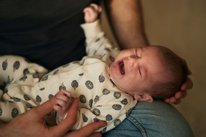 A crying baby in a persons arms, representing the emotional challenges and pain of going no contact with a parent.