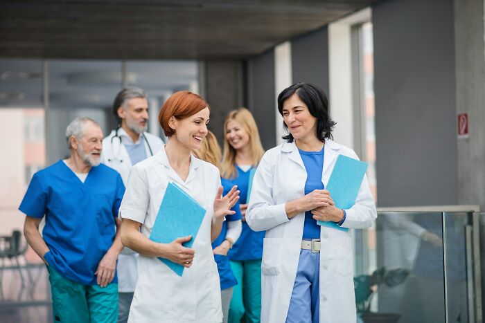 A group of doctors walks through a hospital corridor, discussing medical procedures.