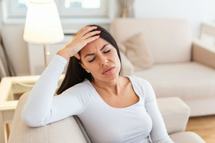 A worried woman holding her forehead, dealing with weirdest body changes in her 30s and 40s