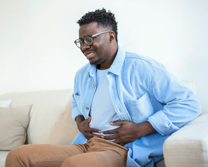 A man experiencing stomach health symptoms, clutching his abdomen in discomfort.