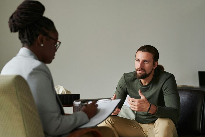 A male patient speaking to a therapist, illustrating the therapeutic process of identifying complex behaviors.
