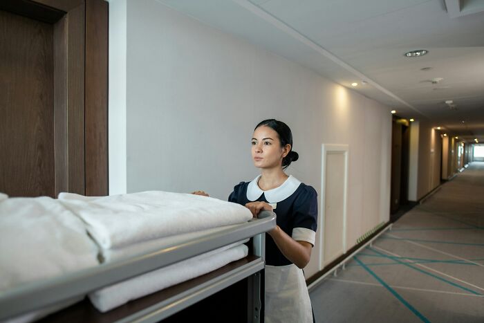 Hotel maid pushing cart with fresh linens in hallway