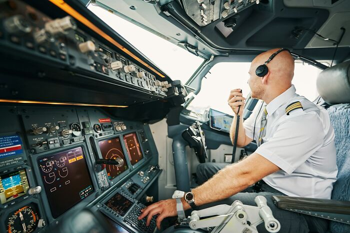 A pilot in the cockpit communicating with air traffic control during a flight with a difficult plane seatmate.