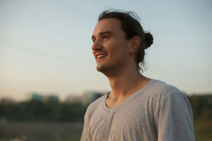 A man with a man bun smiling outdoors, representing dating red flags.