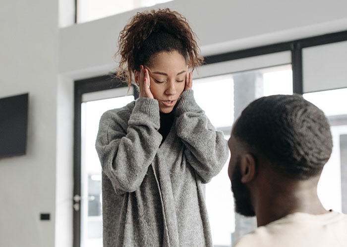 Frustrated woman holding her temples while a man talks to her, illustrating how to argue against vaccines fatigue. Frustrated woman holding her temples while a man talks to her, illustrating how to argue against vaccines fatigue.