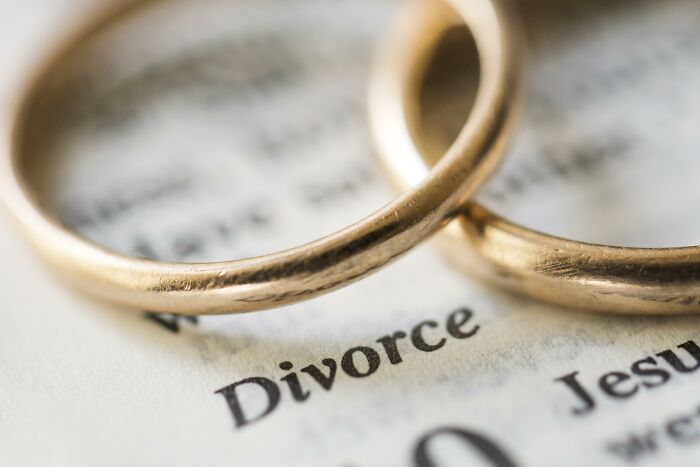 Two gold wedding bands resting on a page featuring the word Divorce, indicating marriage regrets