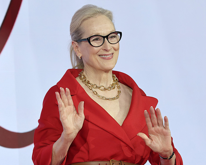A female director smiling, facing religious backlash for her fantasy adaptation.