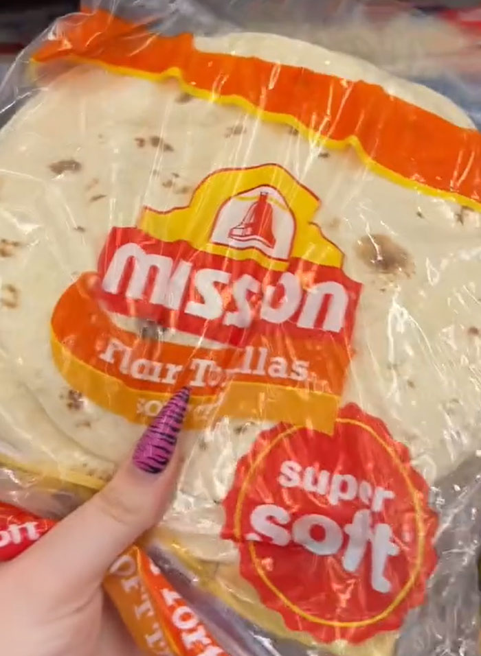 American parents fill the whole cart of groceries. A hand holding a pack of Mission flour tortillas. American parents fill the whole cart of groceries. A hand holding a pack of Mission flour tortillas.