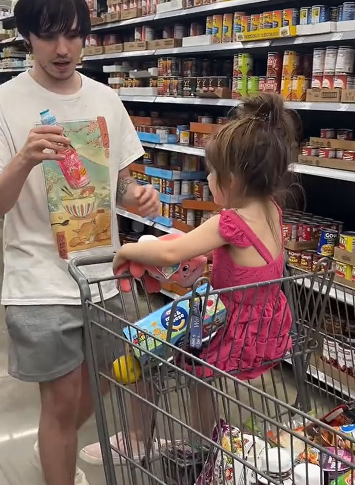A man holding a drink and a young girl in a grocery cart, American parents filling a whole cart of groceries. A man holding a drink and a young girl in a grocery cart, American parents filling a whole cart of groceries.