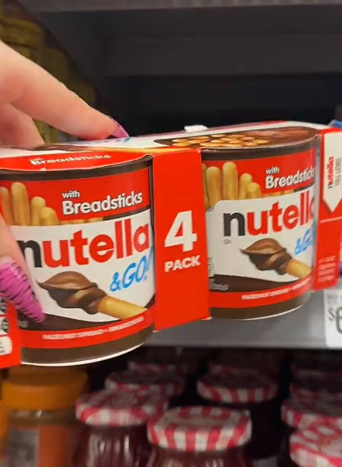American parents shopping for groceries; hand picking Nutella & Go 4-pack with breadsticks from a grocery store shelf. American parents shopping for groceries; hand picking Nutella & Go 4-pack with breadsticks from a grocery store shelf.