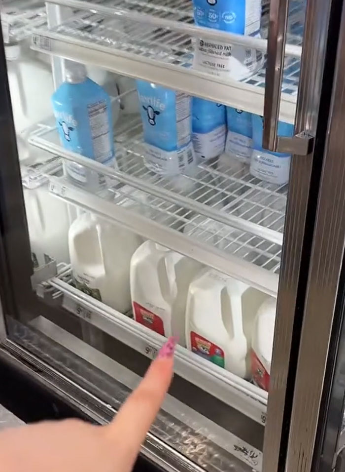 American parents selecting groceries, pointing at milk in a refrigerator. American parents selecting groceries, pointing at milk in a refrigerator.