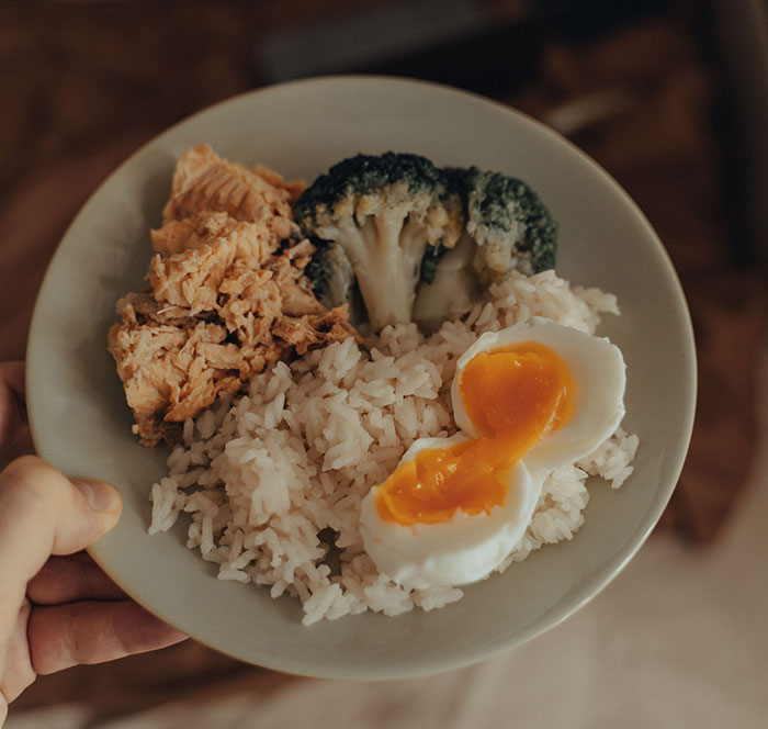 A healthy meal featuring salmon, broccoli, rice, and a soft-boiled egg, representing actual food. A healthy meal featuring salmon, broccoli, rice, and a soft-boiled egg, representing actual food.
