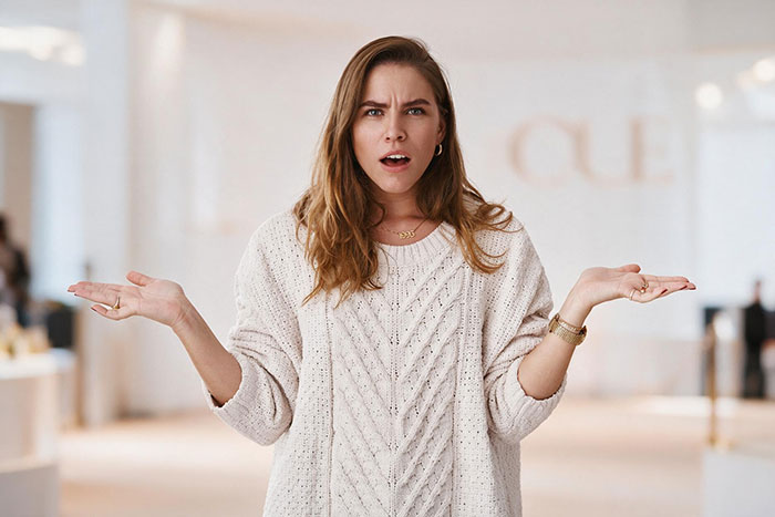 A woman with a confused expression, shrugging her shoulders, about guests paying for a bridal shower.