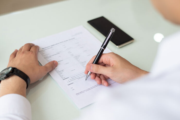 A person signing a document, representing industry secrets in business and legal professions.