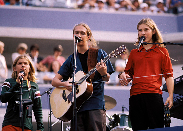 Hanson brothers performing live on stage with guitar and microphones in front of audience
