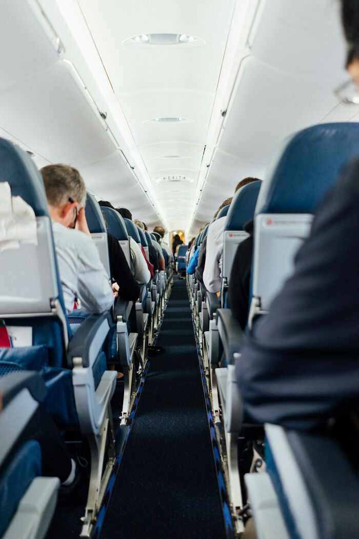 The aisle of an airplane full of passengers, showing the environment cabin crew manage.