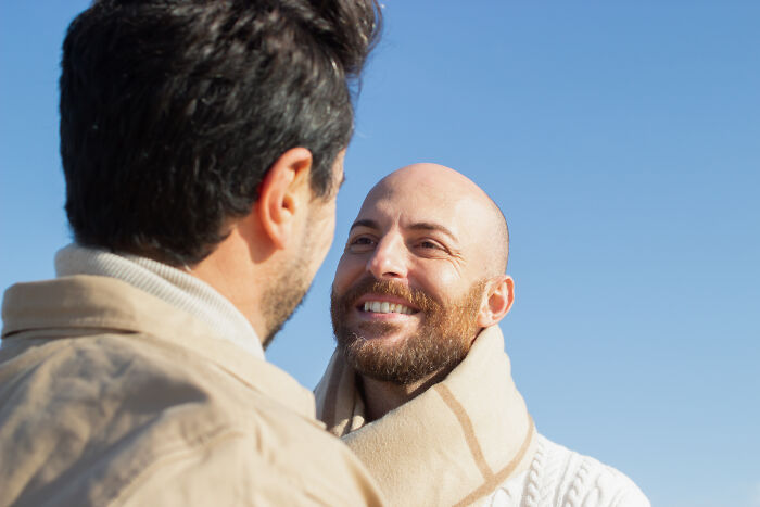 Two men talking closely outdoors, showing a moment of realization often shared by divorced people