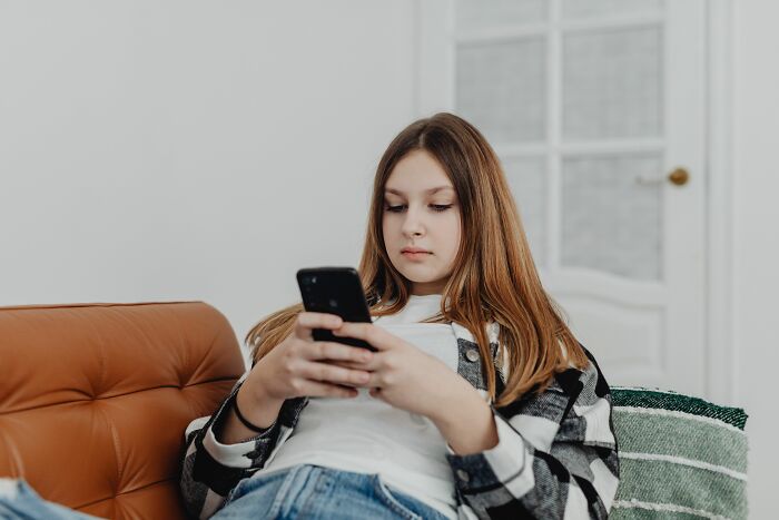 A child looking serious while using a phone, representing kids who might not live their lives freely due to parental control.