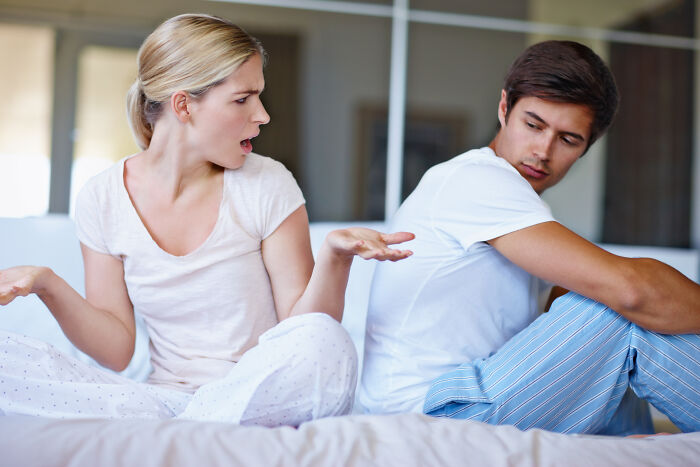 A couple argues in bed, showing frustration and experiencing marriage regrets