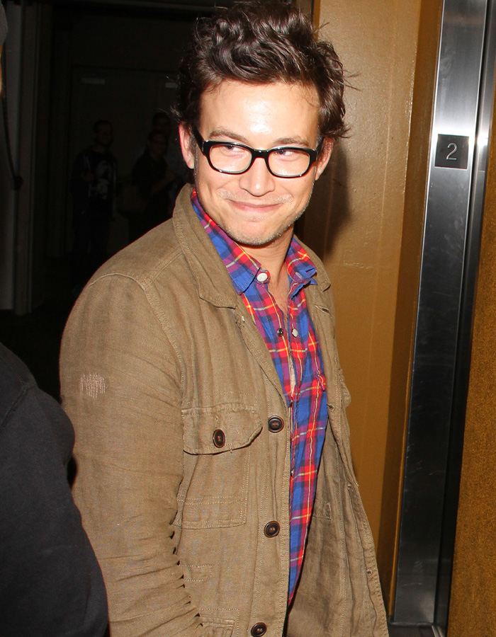 Jonathan Taylor Thomas smiling in glasses and a brown jacket after news of his arrest.