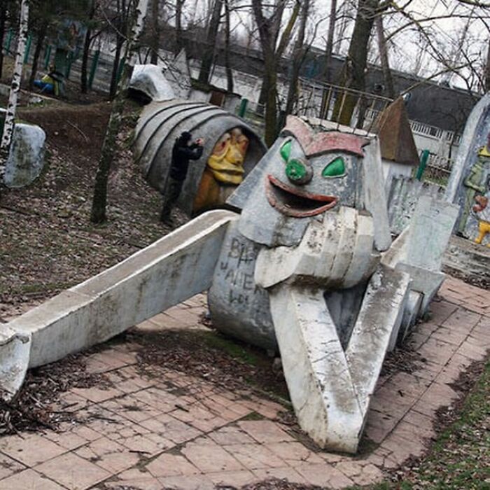 A scary concrete playground slide shaped like a monster with an open mouth. This playground fail looks designed by someone who hates children.
