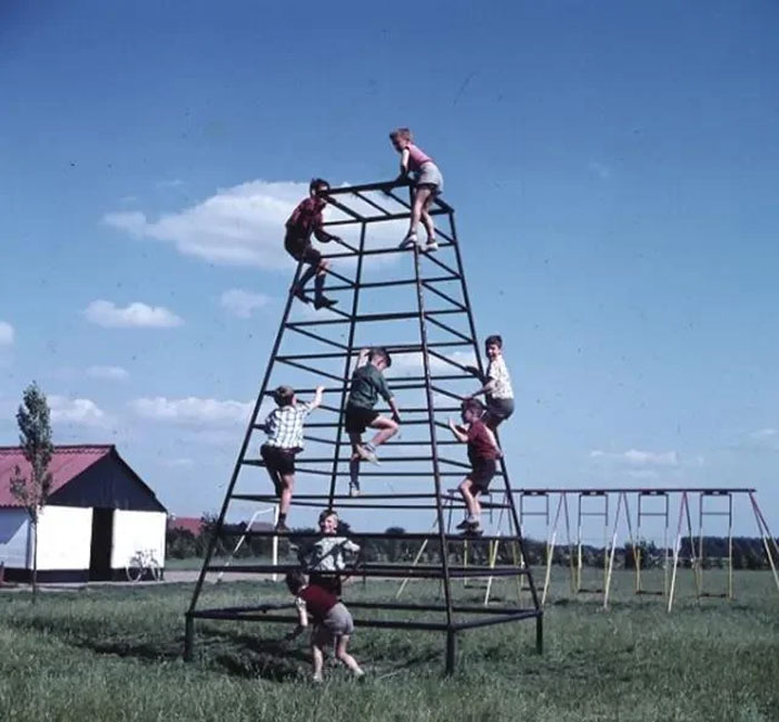 Children playing on a tall, pyramid-shaped climbing structure in a playground, showcasing playground fails.