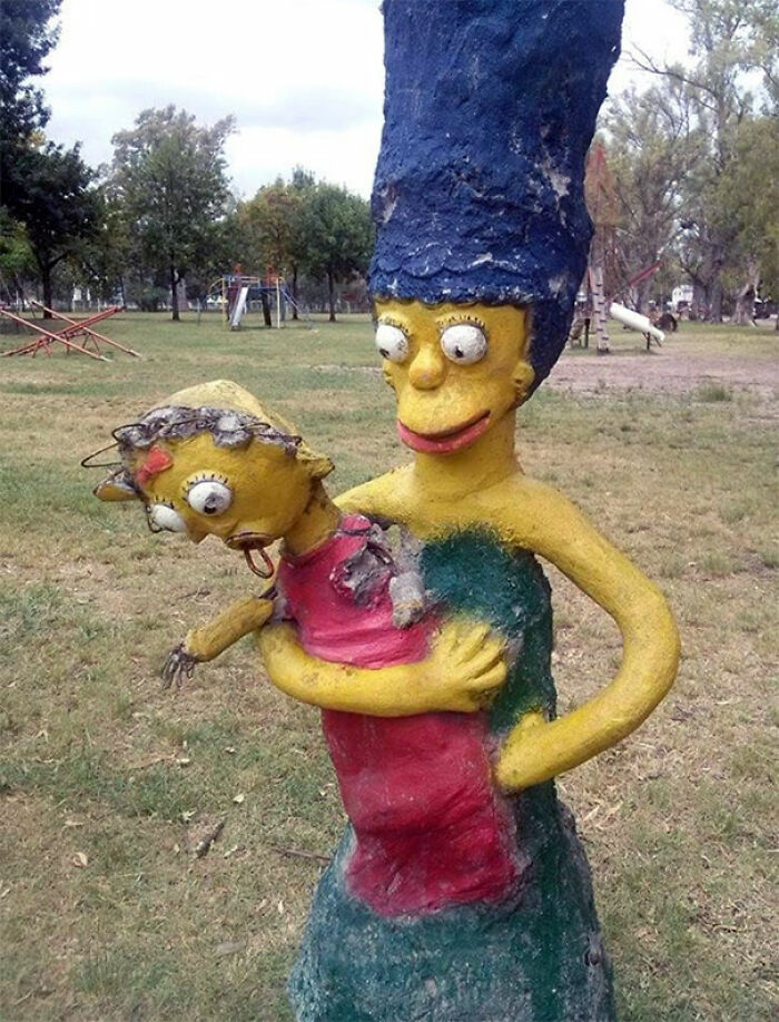 A creepy, poorly sculpted Marge Simpson holding Maggie from the Simpsons in a playground setting, a true playground fail.