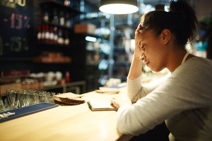 Stressed restaurant worker with head in hand late at bar