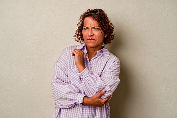 An angry wife with folded arms, symbolizing a spouse threatening to drop her husband from her health insurance. An angry wife with folded arms, symbolizing a spouse threatening to drop her husband from her health insurance.