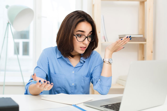 A woman looks frustrated and confused at a laptop, illustrating issues with separated finances.