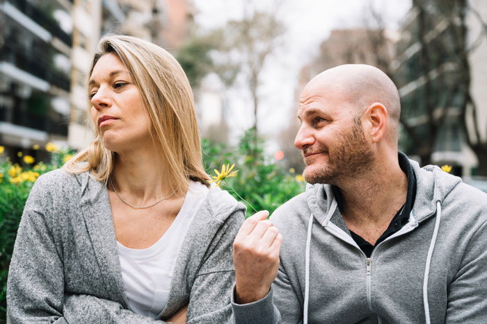 A wife looks away from her husband, upset about his spending and separated finances.