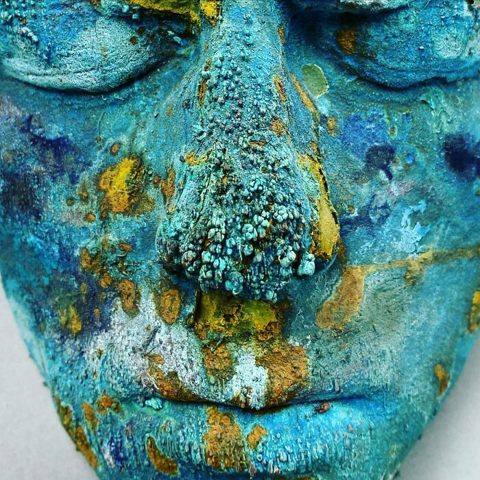 Close-up of a vibrant blue underwater sculpture face with textured coral-like growth, an ocean floor art piece.