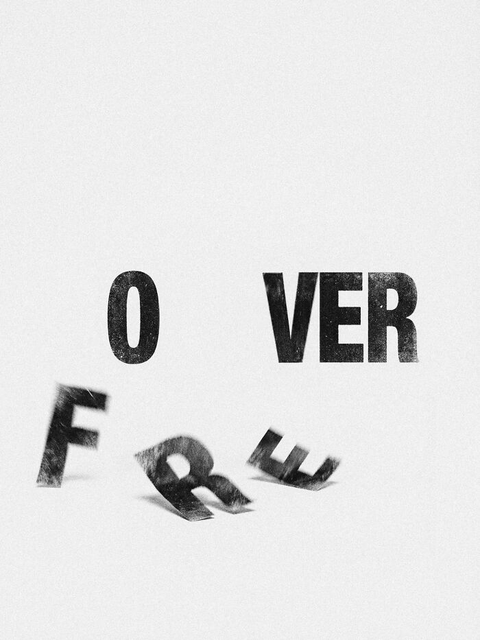 A black and white image showing the word 'OVER' in focus and the letters 'F R E' scattered and blurry, depicting surreal imagery.