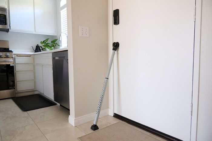 A door security bar in a kitchen doorway, illustrating a safety tip for women living alone to protect themselves.