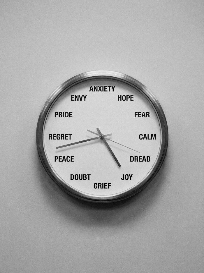 A black and white wall clock with emotions like anxiety, fear, joy, and peace instead of numbers, symbolizing distorted reality.