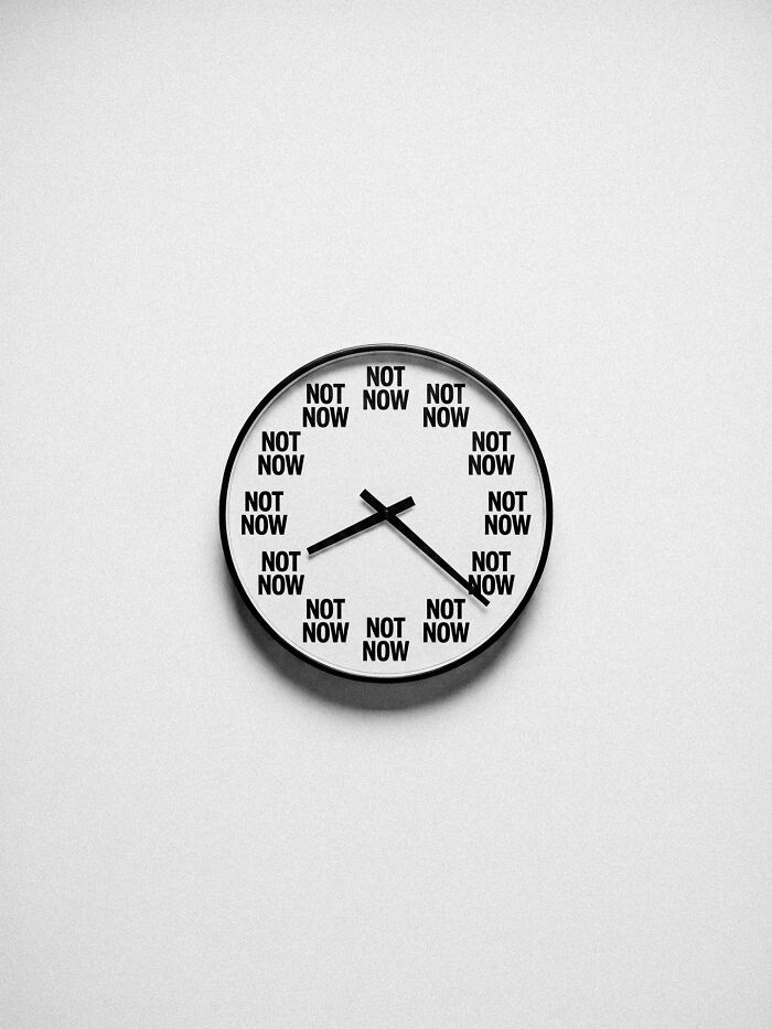 A black and white image of a clock with the words NOT NOW instead of numbers, a surreal image by Marcus Wallinder.