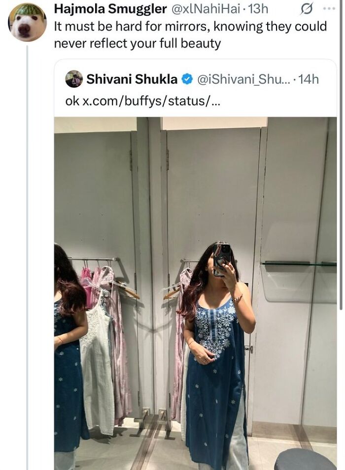 Woman taking mirror selfie wearing blue embroidered dress in dressing room