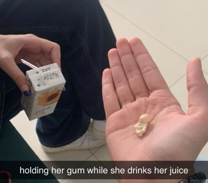 Hand holding chewed gum with juice box and person sitting in background