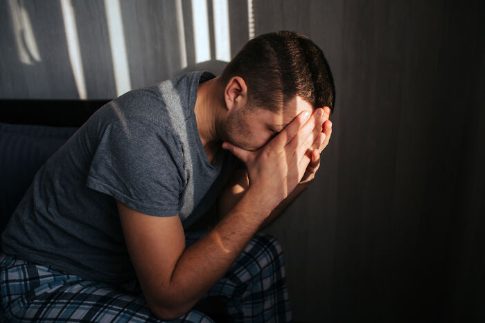 A man sitting with his head in his hands, appearing distressed, possibly contemplating divorce.