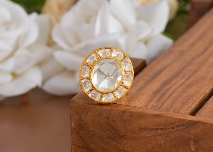 A close-up of a gold ring with a large clear gem, symbolizing luxury industries that are about to collapse.