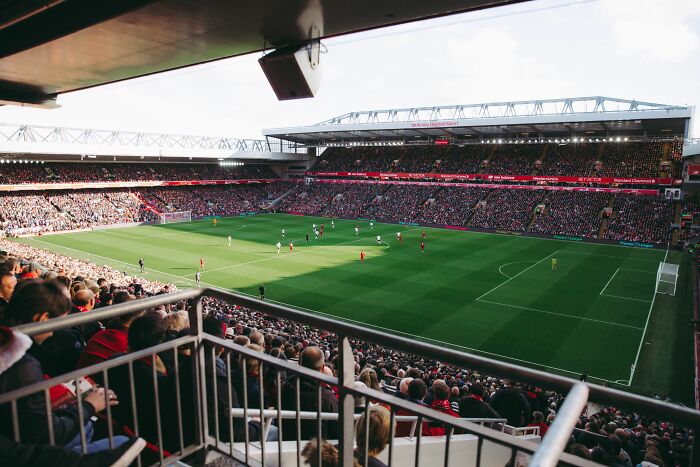 A vibrant stadium packed with fans watching a soccer game, symbolizing industries about to collapse.