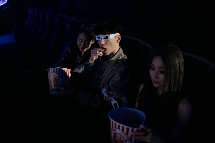 People wearing 3D glasses watching a movie in a dark cinema, depicting entertainment industries that are about to collapse.