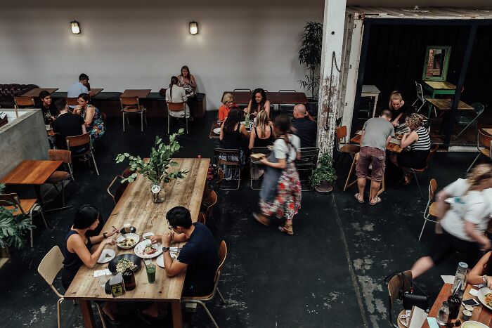 An overhead view of a bustling cafe, representing dining industries that are about to collapse.