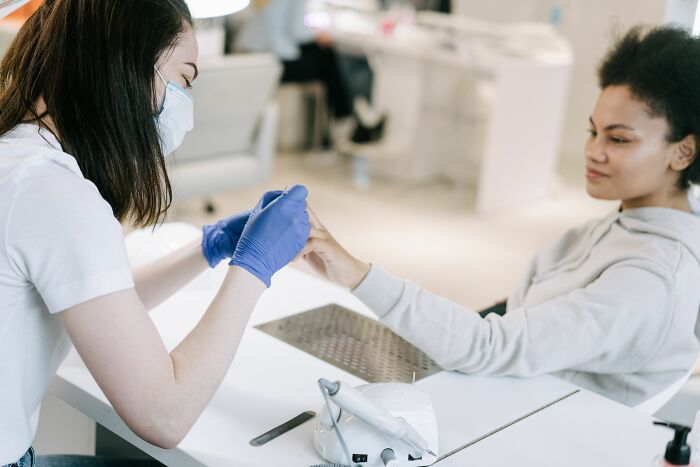 Nail technician working on a client's nails, an industry about to collapse.