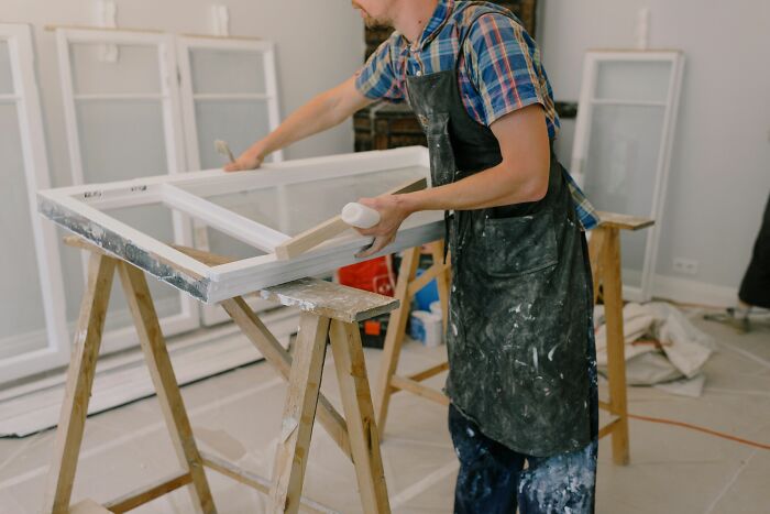 Man repainting old window frames, an industry about to collapse.
